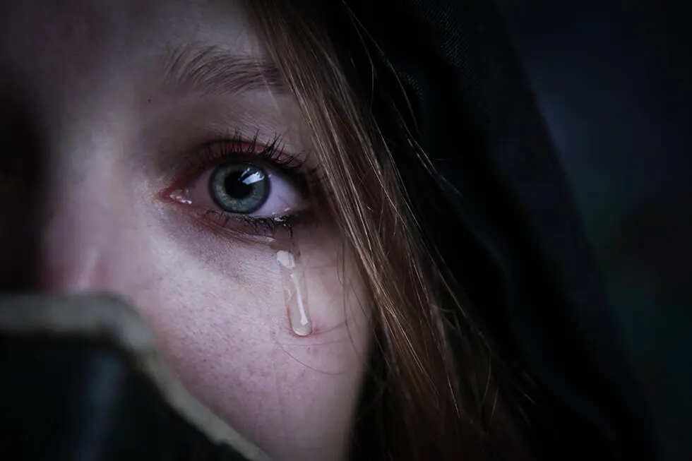 Close-up of a tearful eye with a somber expression
